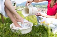 Frau erhält ein Milchwell Fußbad auf einer grünen Wiese