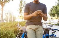 Mann lenkt an seinem Rad und tippt auf dem Smartphone