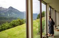 Paar im Bademantel genießt die Aussicht auf Berge vom Wellnessbereich aus