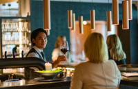 Barkeeper überreicht ein Glas Rotwein an eine Damen an der Bar