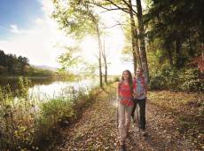 Paar wandert einen Waldweg entlang nebenan ein Fluss im Allgäu