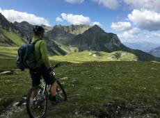 Biker genießt die Aussicht auf eine Berglandschaft im Sommer mit Wolken und grünen Wiesen
