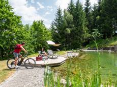 Person auf einem Bike unterhält sich mit einer Frau auf einer Liege am Alpinpark