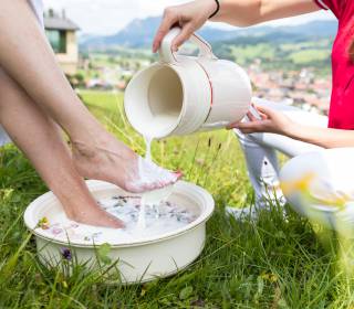 Frau erhält ein Milchwell Fußbad auf einer grünen Wiese