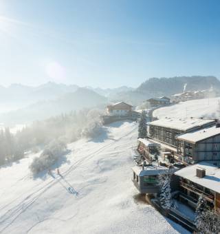 Hotel Tanneck eingeschneit im Winter mit Wintersonne über den Gipfeln