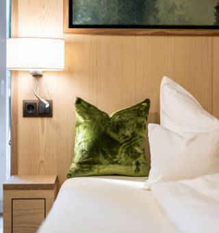 Grünes Zierkissen auf einem Hotelbett