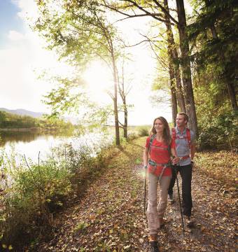 Paar wandert einen Waldweg entlang nebenan ein Fluss im Allgäu