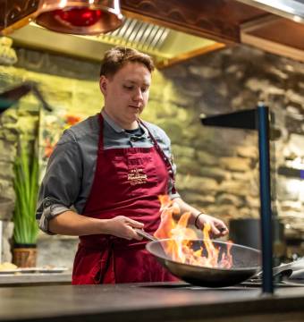 Koch schwingt flammende Pfanne