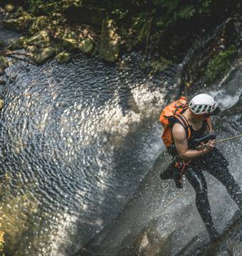 Person beim Abseilen an einem Wasserfall