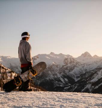 Person auf der Piste mit einem Snowboard in der Hand
