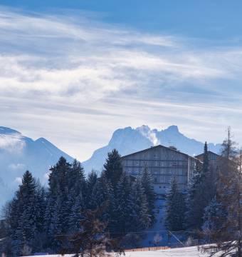 Winterurlaub im Allgäu - Berglandschaft und Tannen dazwischen ein Hotel