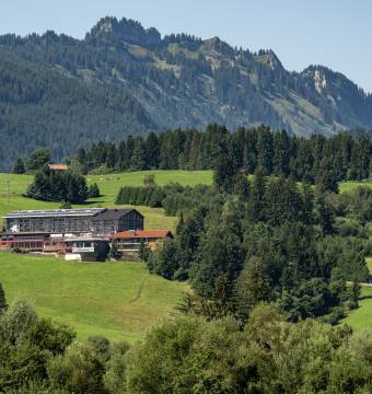 Hotel Tanneck zwischen grünen Wiesen und Bergen im Sommer