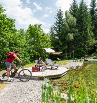 Person auf einem Bike unterhält sich mit einer Frau auf einer Liege am Alpinpark