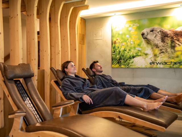 Zwei Personen liegen im Bademantel auf Infrarot-Liegen und entspannen