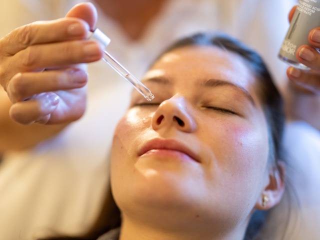 Frau erhält eine Gesichtsbehandlung mit einem Serum