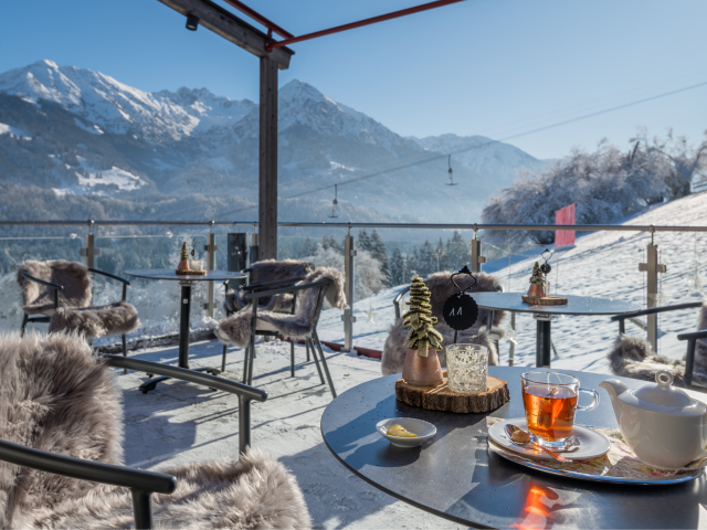 Sitzbereiche mit Fell draußen mit Blick auf winterliche Landschaft und Berge