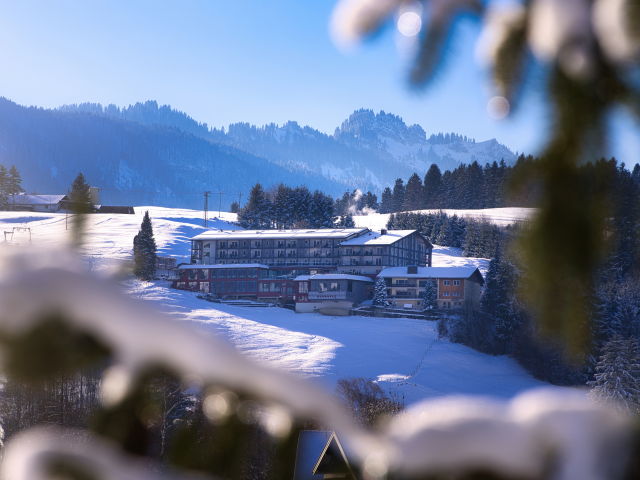Hotel Tanneck im Winter mit schneebedeckten Bergen und Tannen