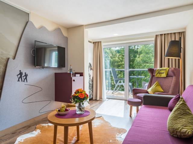 Hotelzimmer mit lila Sofa und Wanderelementen an der Wand