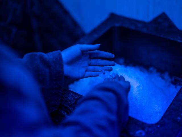 Person holt Eis aus einem Eisbrunnen