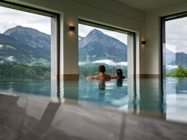 Pärchen genießt die Aussicht vom Infinity Pool aus zu den Bergen