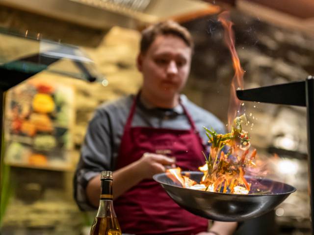 Koch schwingt eine Pfanne mit feurigen Inhalt